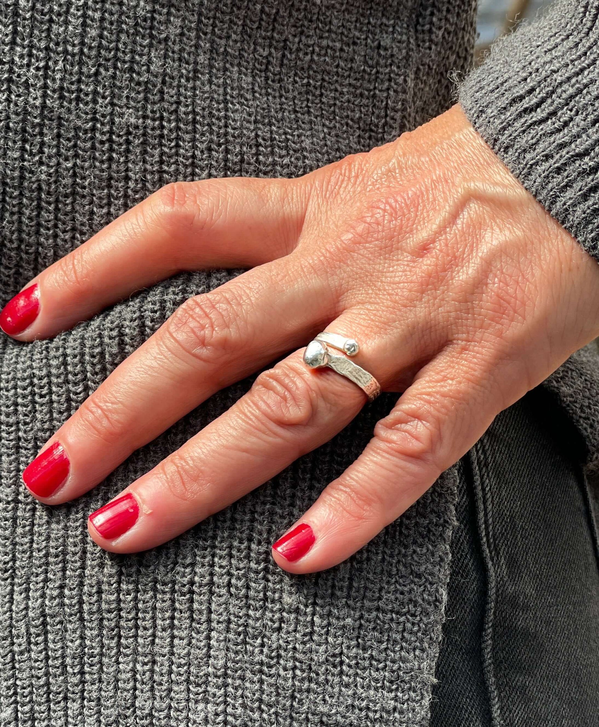 Close-up of a hand wearing the Radiant Loop Ring, showcasing its elegant design and sparkle, perfect for adding sophistication and style to any outfit.