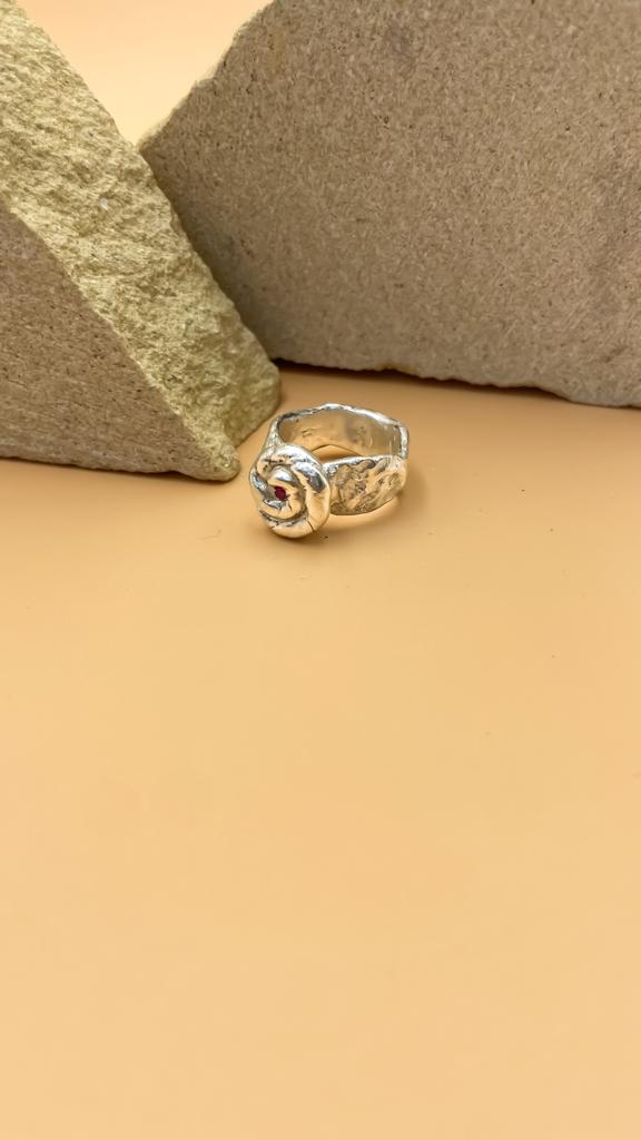 Rose Radiance Ring in 925 sterling silver with zircon stone displayed on a tan background against rocks